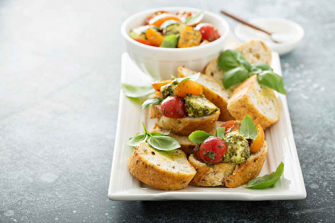 Caprese bruschetta with cherry tomatoes, mozarella and basil pesto