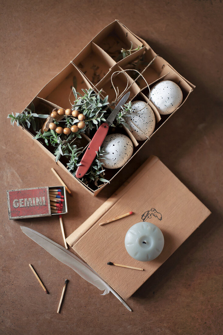 Speckled eggs, chickweed, matches and candle in egg box