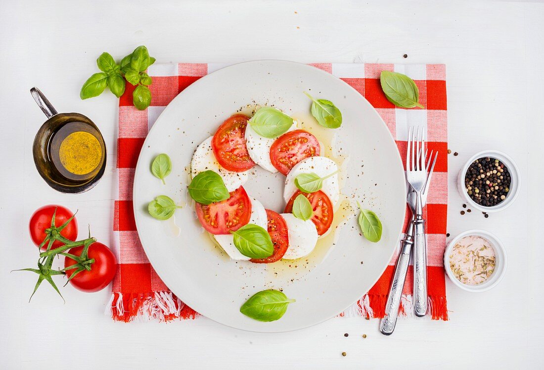 CLassic Italian Caprese salad with tomatoes, mozzarella di Buffala and fresh basil on red and white checkered napkin