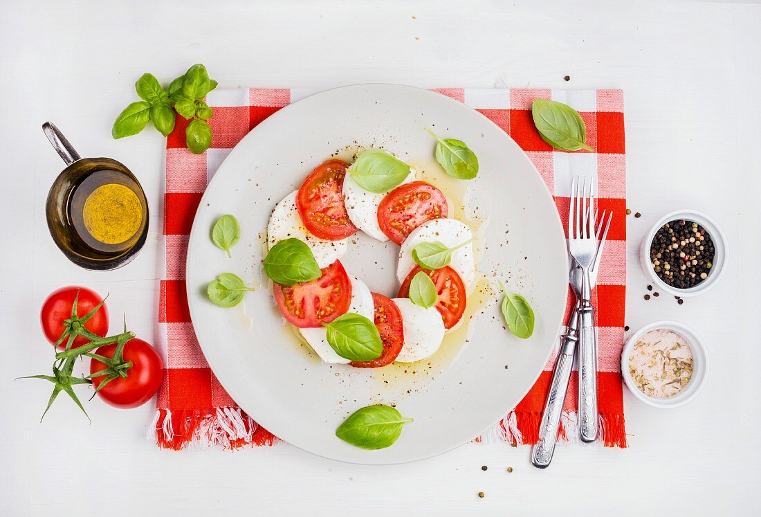 Italienische Caprese mit Tomaten, Büffelmozzarella und Basilikum auf rot-weiß karierter Serviette
