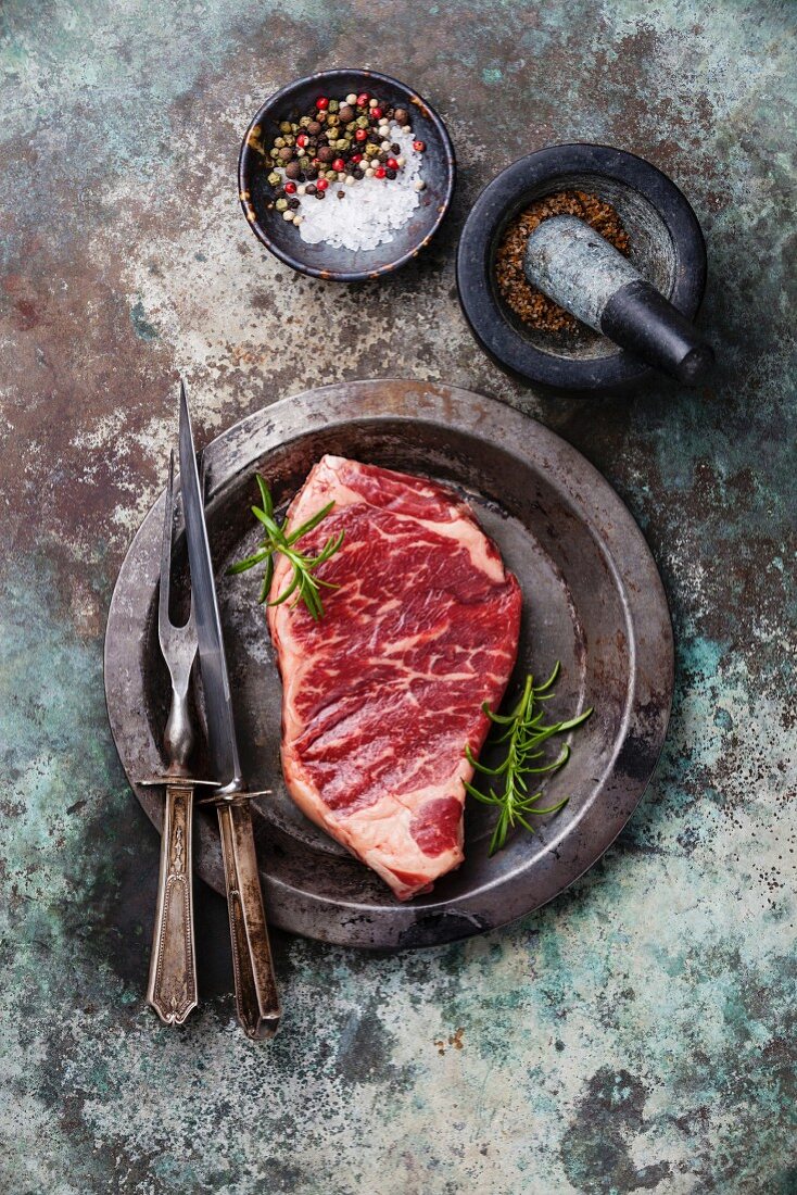 Rohes Striploin Steak und Gewürze im Mörser auf Metalluntergrund
