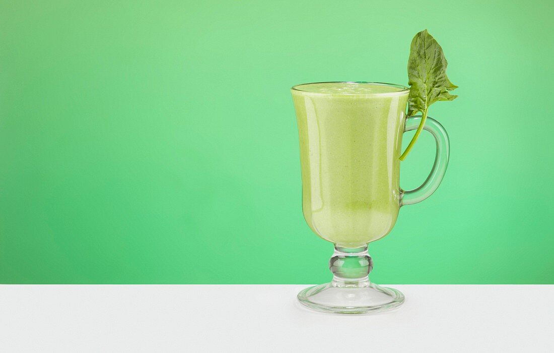 Green Smoothy in the glass on green background