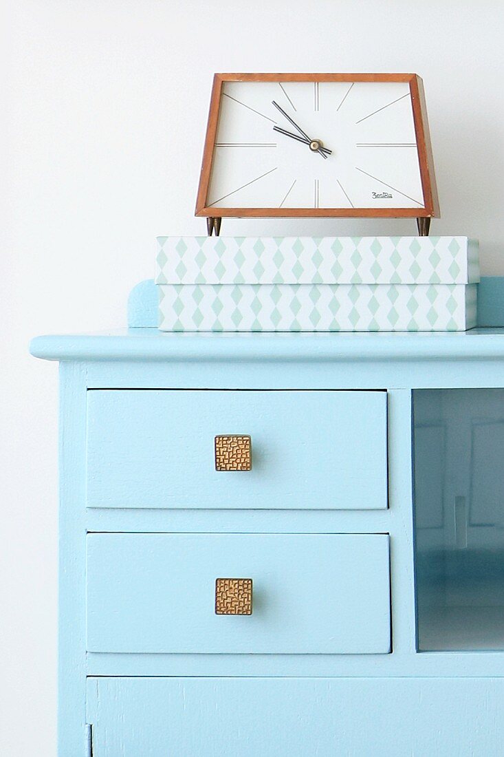 Retro alarm clock and box on top of blue cabinet