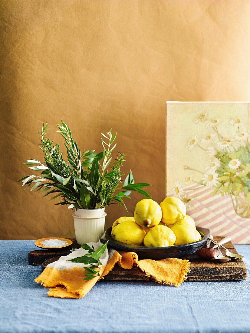 Still life with quince, herb bouquet and salt on wooden cutting board