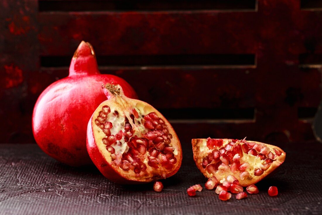 Pomegranate Seeds, some peeled and whole on a dark background