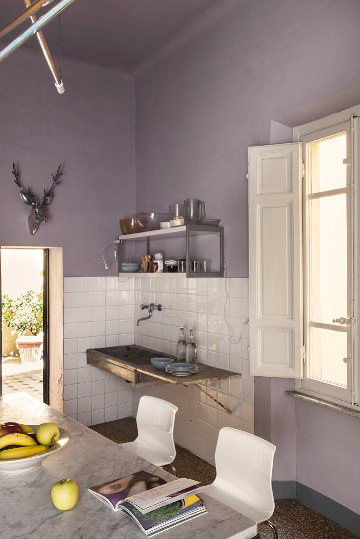 Dining area and old sink on lilac wall in kitchen