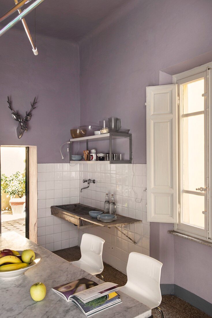 Küche mit Essplatz und altem Spülstein an fliederfarbener Wand
