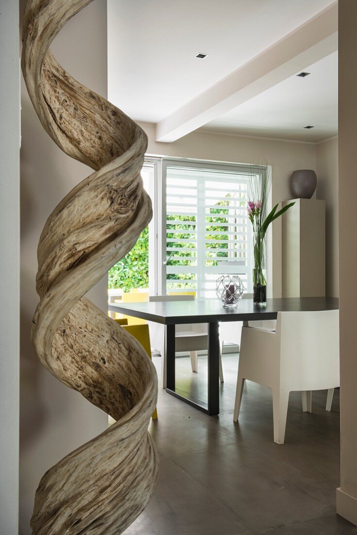 Wooden sculpture in front of black dining table and designer chair