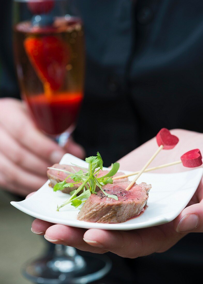 Hand hält Teller mit Filet-Häppchen