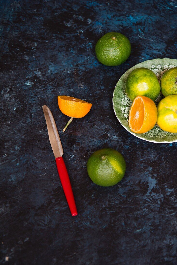 Various citrus fruits on a plate with a knife next to it