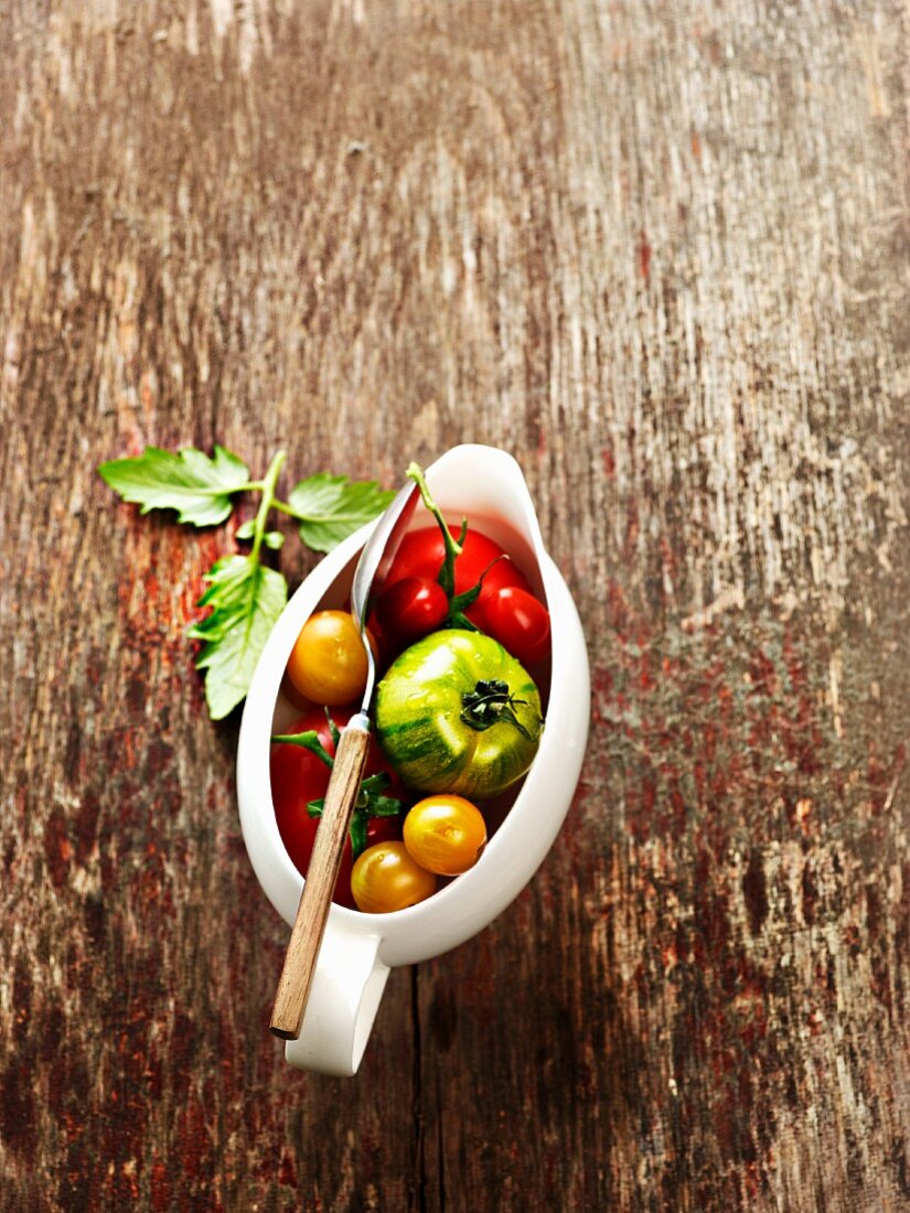 Various tomatoes in a saucer on a wooden background