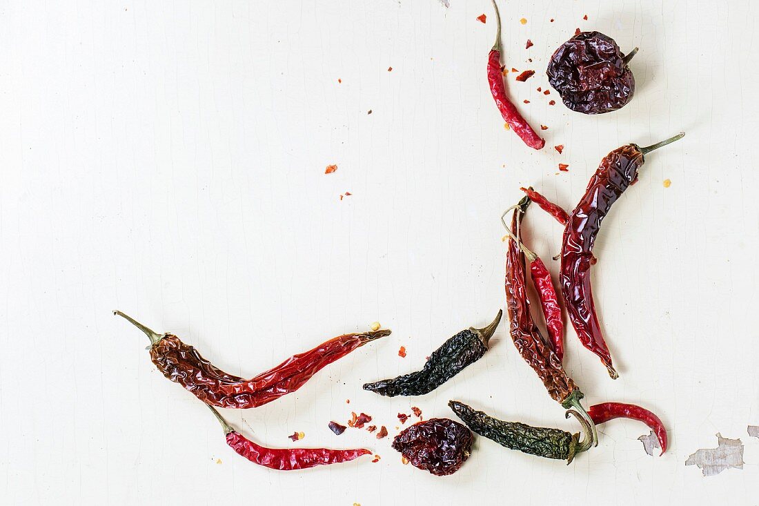 Assortment of dryed red hot chili peppers over white wooden background