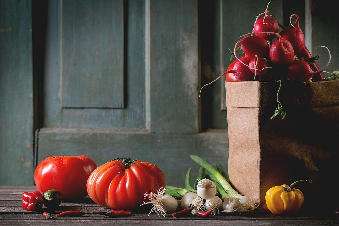 Frische Tomaten, Chilischoten, Frühlingszwiebeln und ein Bund Radieschen in Papiertüte