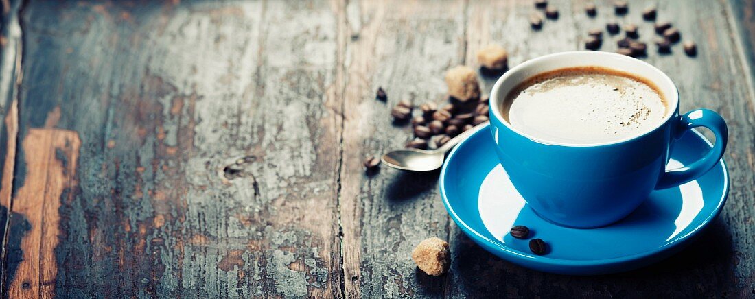 Blaue Kaffeetasse und Kaffeebohnen auf Vintage Holzuntergrund