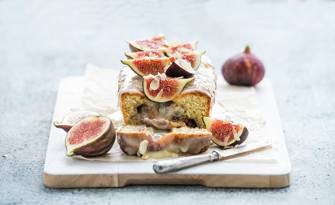 Loaf cake with figs, almond and white chocolate on white serving board