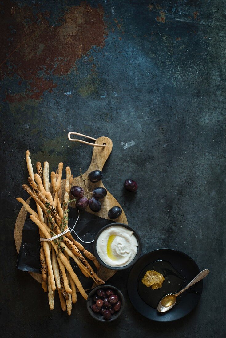 Vollkorn-Grissini mit Oliven, Trauben und Joghurtdip (Draufsicht)