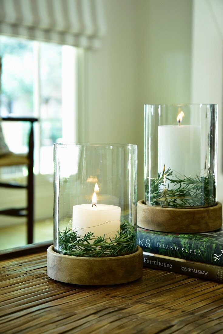 Pillar candles in glass and wood lanterns decorated with sprigs of rosemary