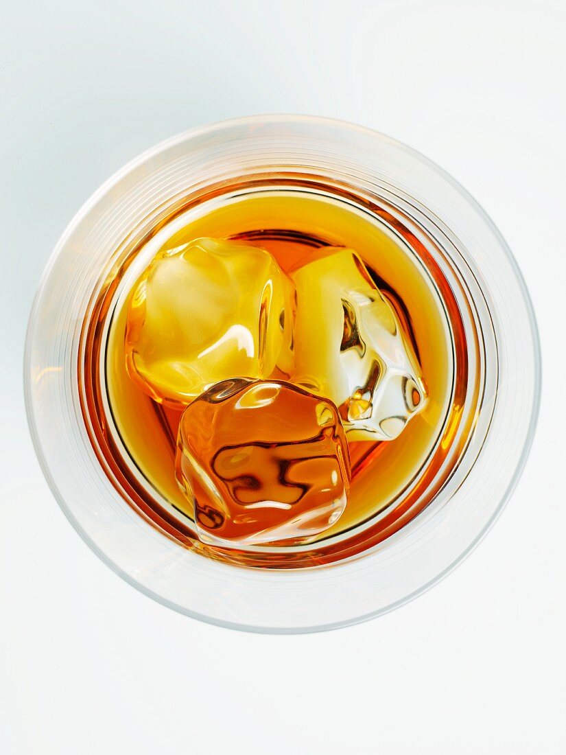 Blick von Oben in ein Glas Whisky mit Eiswürfeln