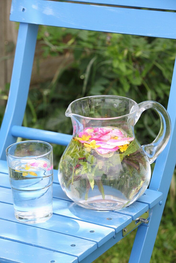 Wasser mit Kräutern und Blüten im Glas und Glaskrug