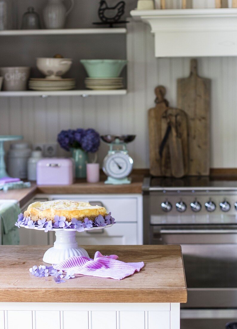 Cheese Cake dekoriert mit Blüten auf Kuchenständer in Landhausküche