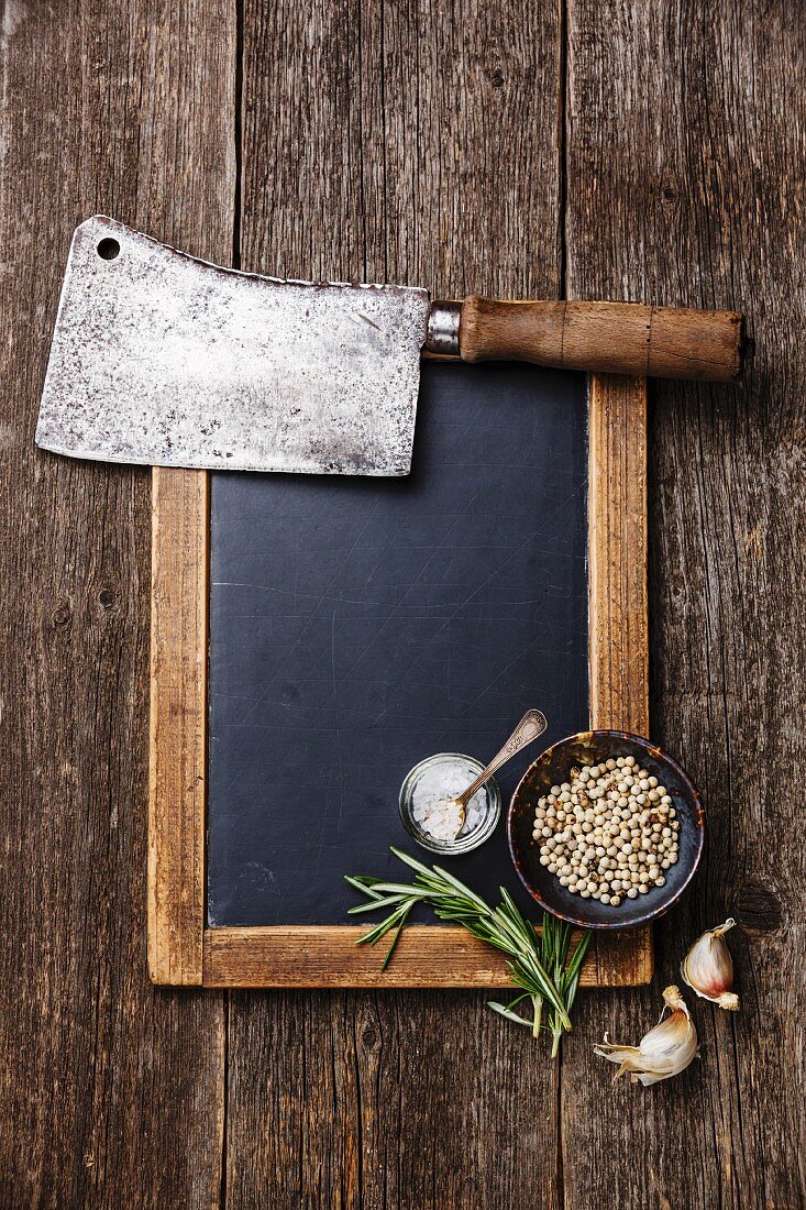 Vintage slate chalk board, Butcher meat cleaver and spices on wooden background