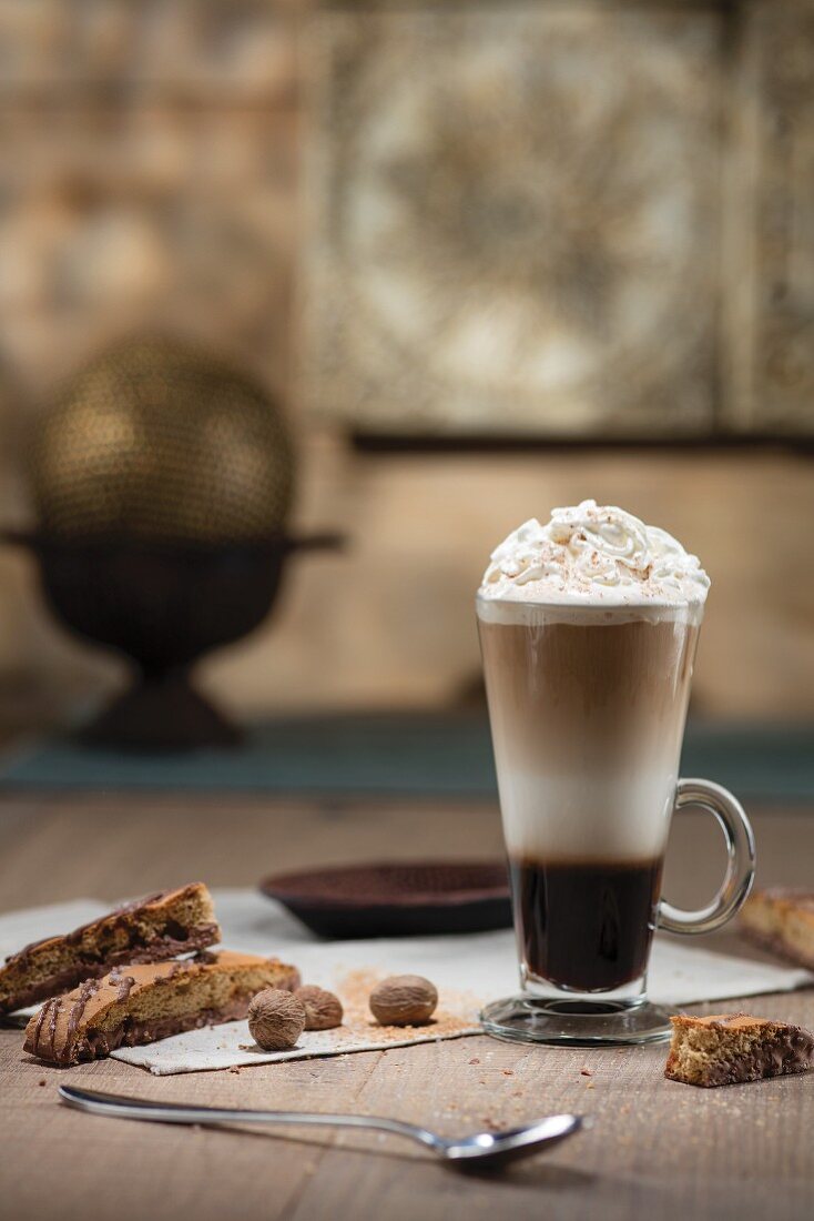 Espresso cocktail layered in tall glass with whipped cream nutmeg and biscotti