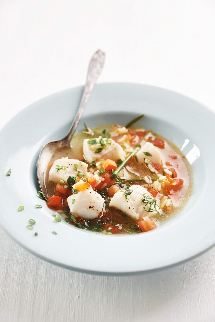 Mediterrane Fischsuppe mit Reis, Knoblauch und Tomaten