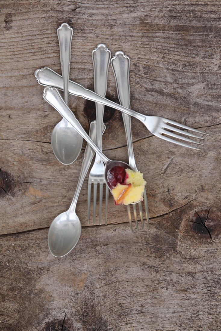 A spoon of a cherry and quark bake with dessert cutlery (top view)