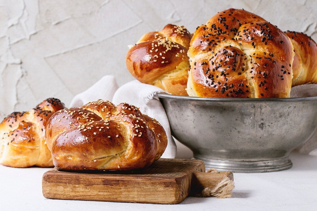 Heap of sweet round sabbath challah bread with white and black sesame seeds in vintage metal bowl
