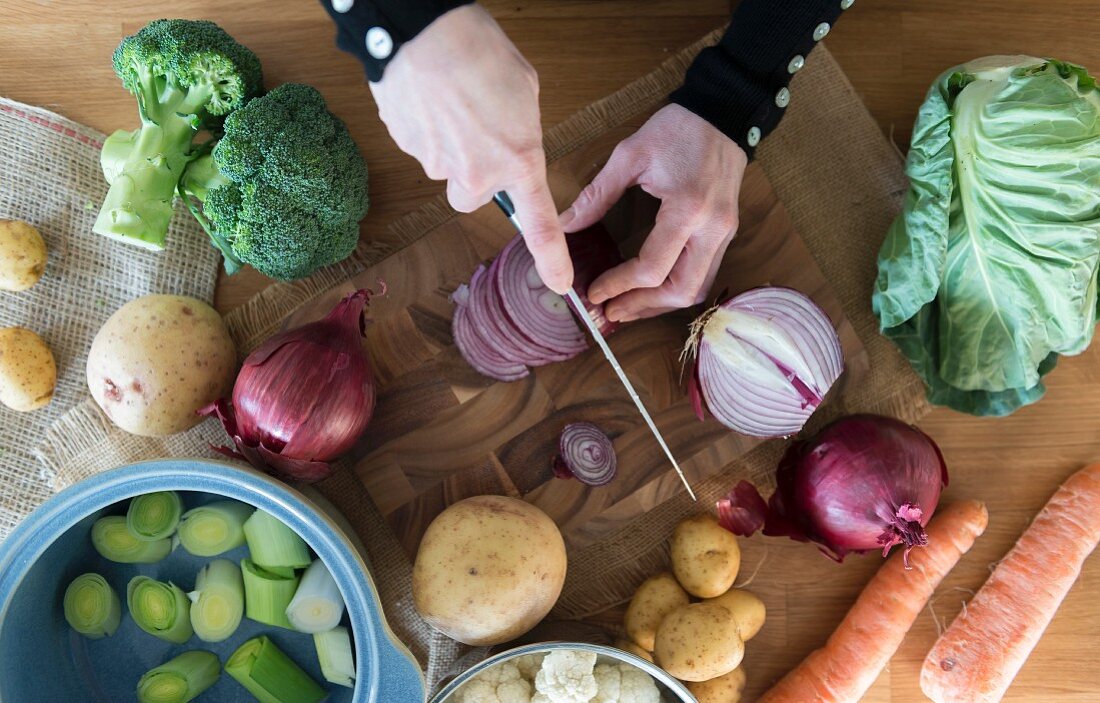 A womans hands slicing vegetables for a recipe