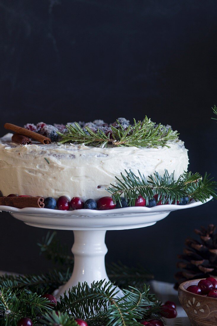 Englischer Weihnachtskuchen mit frischen Beeren, Zimtstange und Tannenzweigen dekoriert