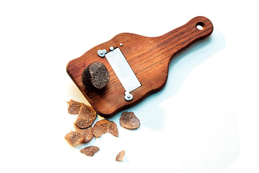 A wooden truffle slicer and black truffle