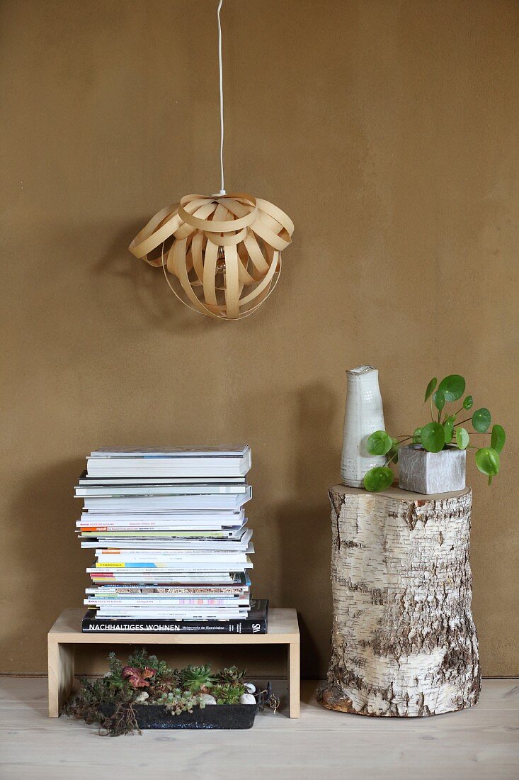 Lampshade made from wood veneer above stacked magazines and tree stump