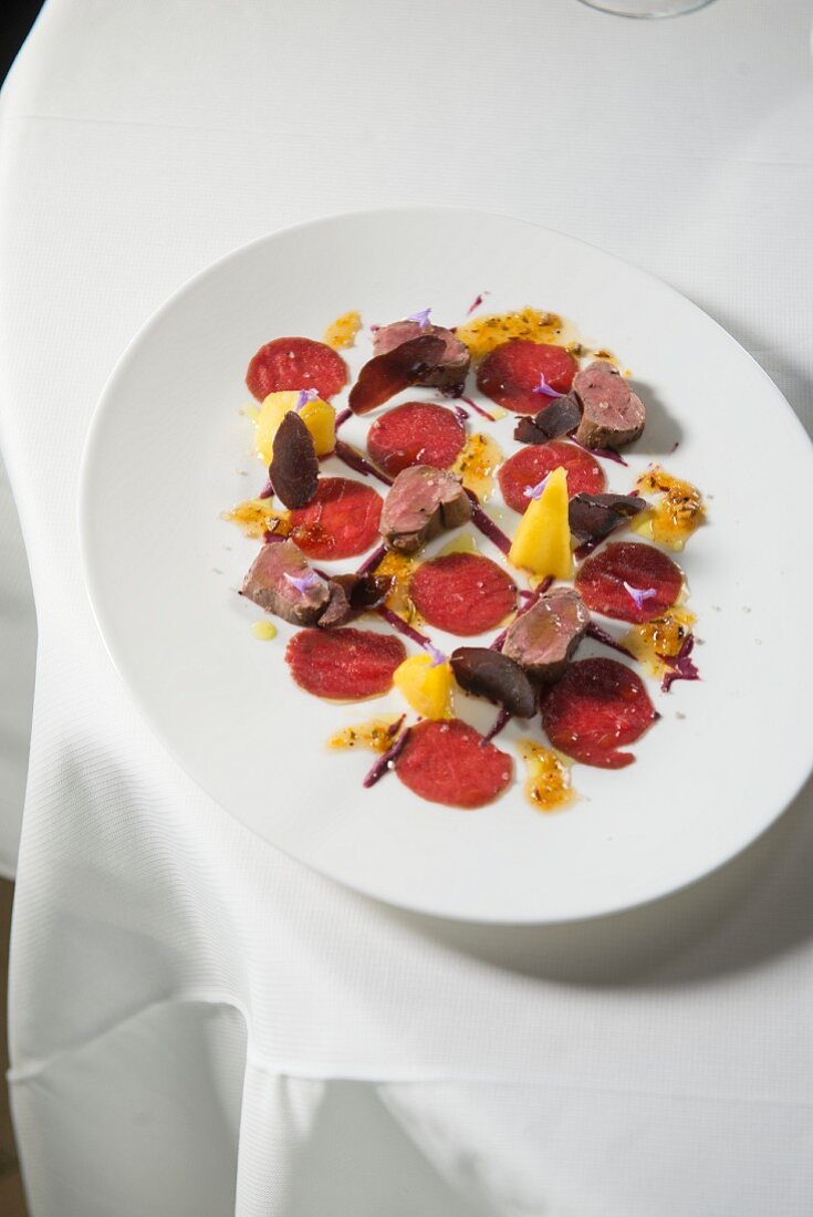 Hirschfilet, Gamscarpaccio, Blaubeersenf, Gewürzhonig und Safran-Apfel aus dem Restaurant Obauer in Werfen, Salzburg, Österreich