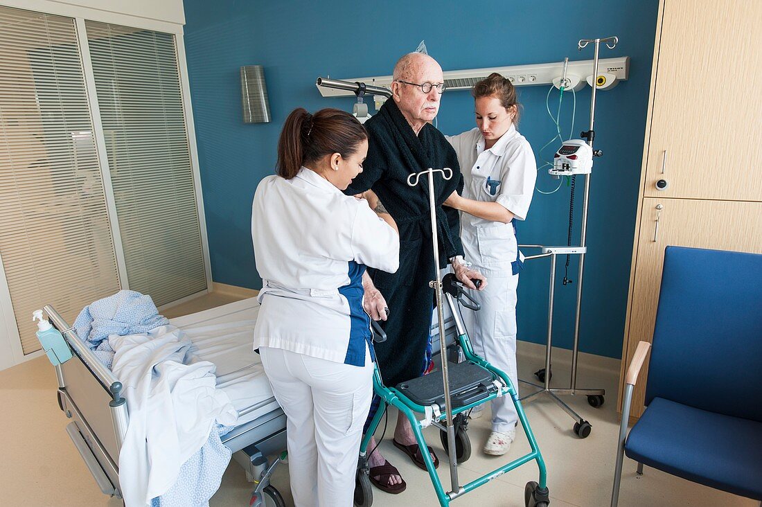Nurses helping senior male ward