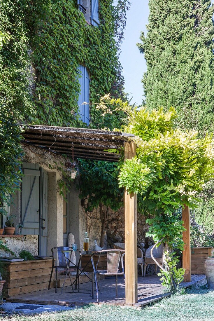 Vintage metal chairs on rustic terrace outside climber-covered house