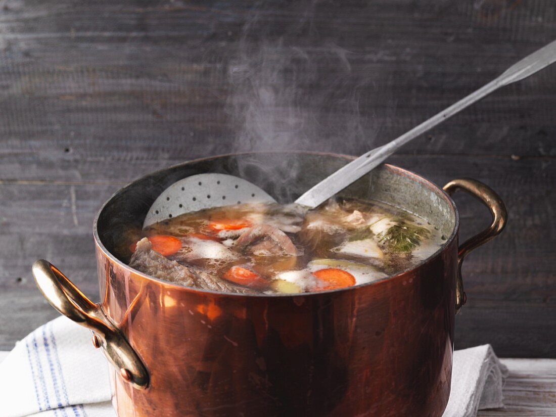 A copper pot with homemade, steaming meat stock