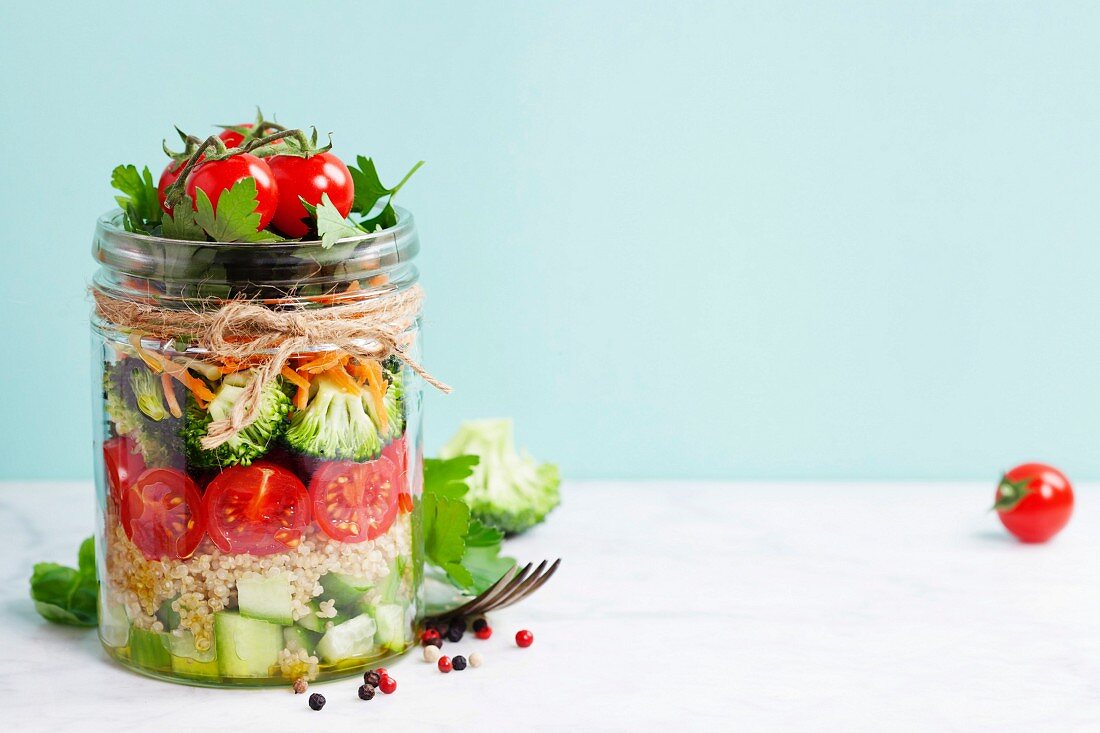 Gesunde Ernährung: Quinoa mit Tomaten, Brokkoli und Gurke im Weckglas geschichtet