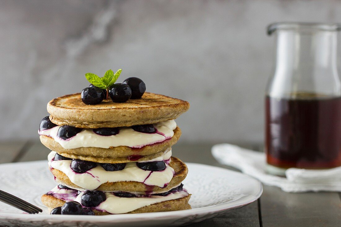 Pancake-Stapel mit Joghurt, Sahne, Heidelbeeren und Ahornsirup