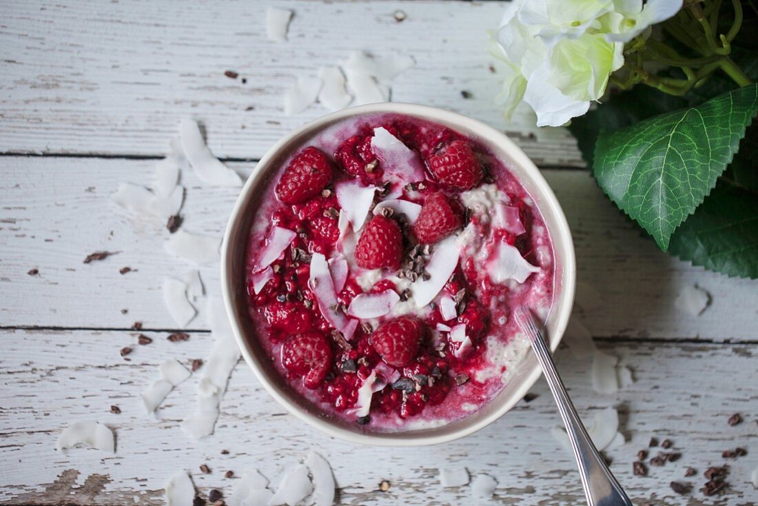 Coconut chia pudding with raspberry sauce, coconut flakes and cacao nibs in a bowl