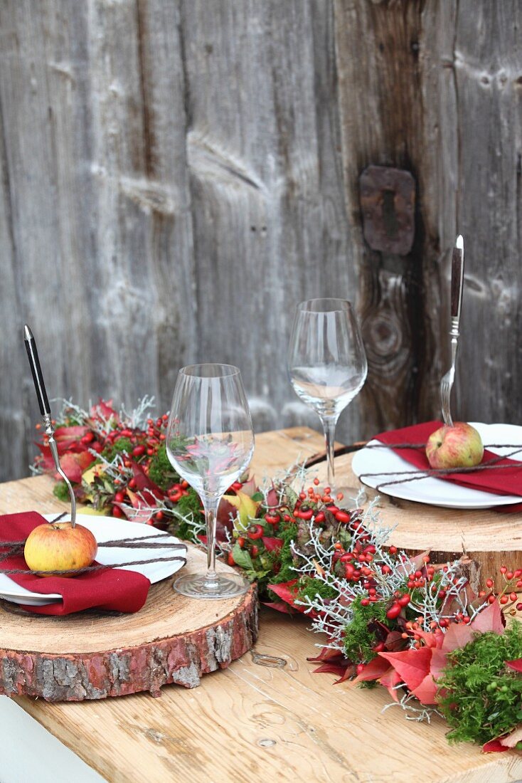 Autumnal place settings on table with rustic wooden boards as place mats and apples on plates