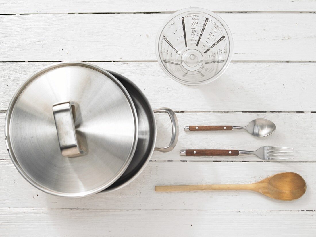 Kitchen utensils: cooking pot, measuring cup, spoon and fork