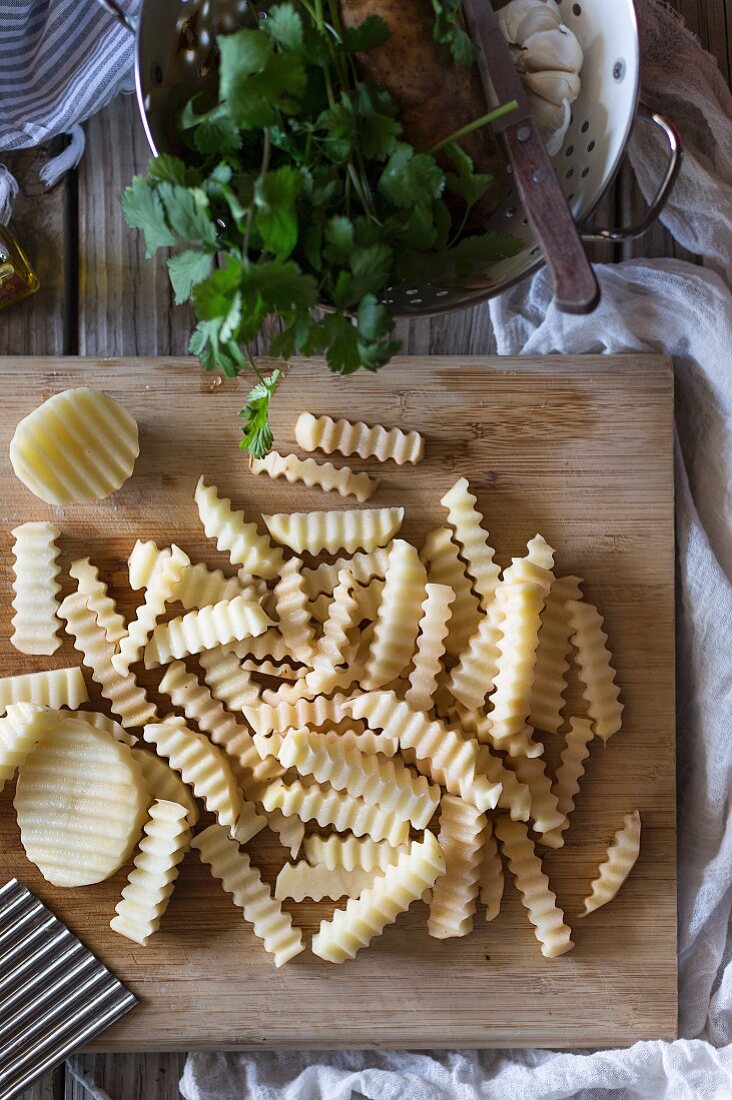 Rohe Wellenschnitt-Pommes auf Holzbrett (Aufsicht)