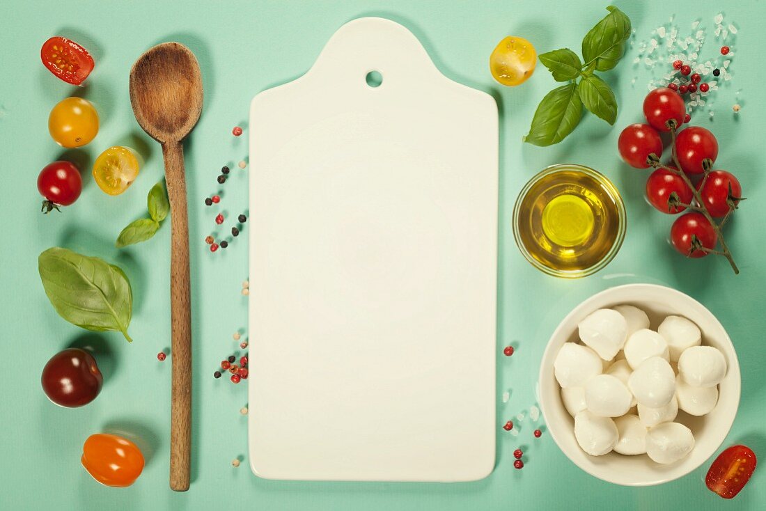 White ceramic serving board and caprese salad ingredients over light blue background