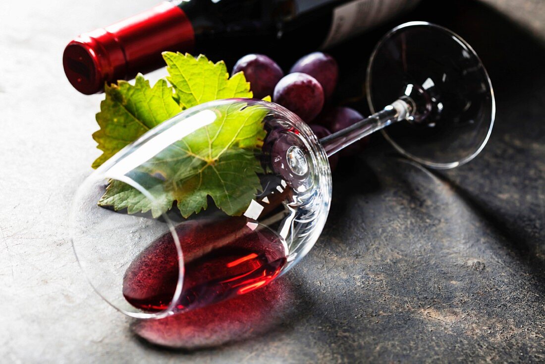 Umgekipptes Glas Rotwein auf dunklem Hintergrund