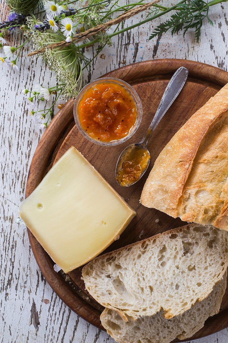 Käse, Bauernbrot und Aprikosenchutney auf Holzbrett