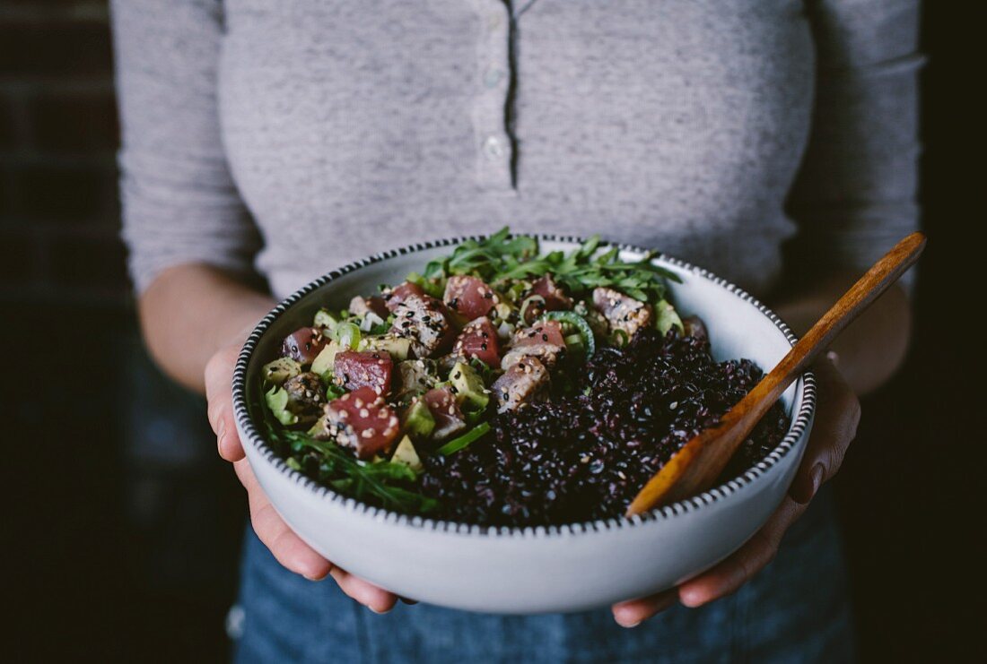 Frau hält Salatsschüssel mit Seared Thunfisch in Sesamkruste und schwarzem Reis