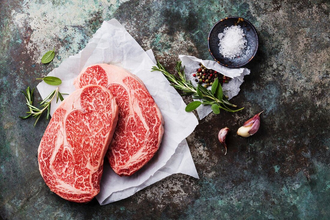 Raw fresh marbled meat Black Angus Steak Ribeye and seasonings on metal background