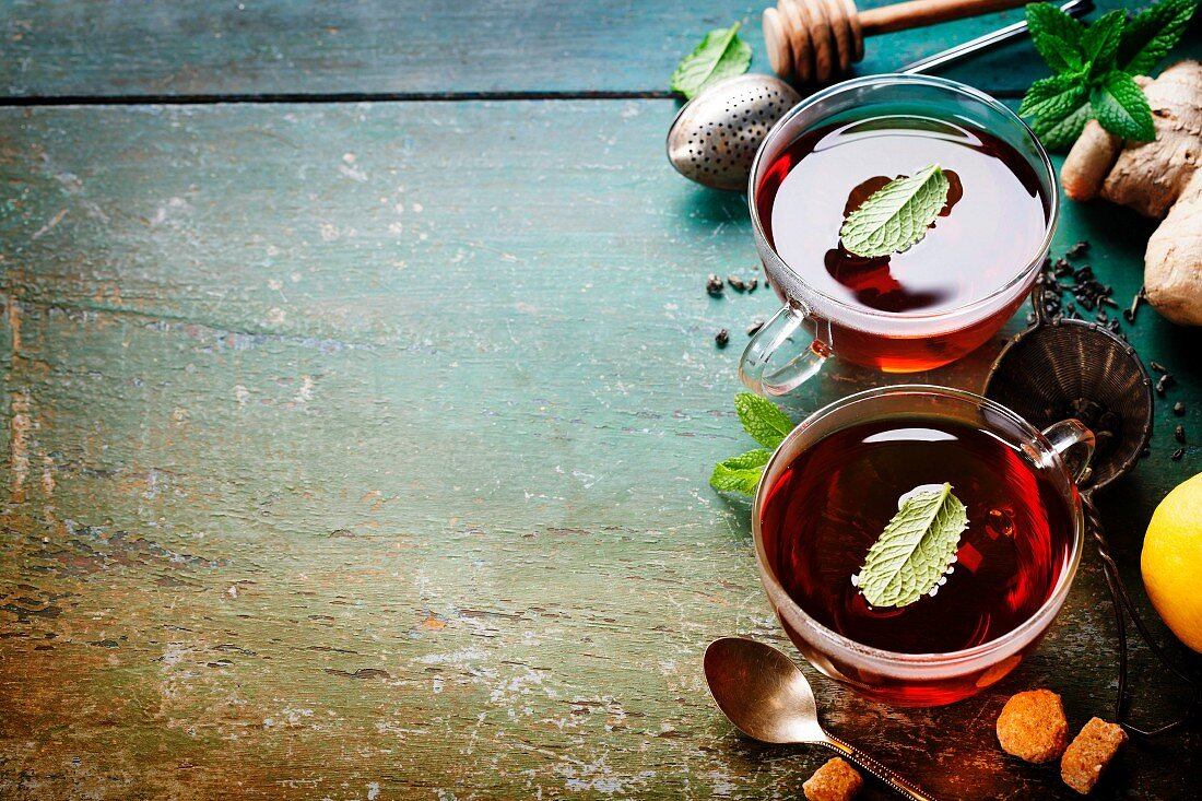 Tea with mint, ginger and lemon on old wooden table
