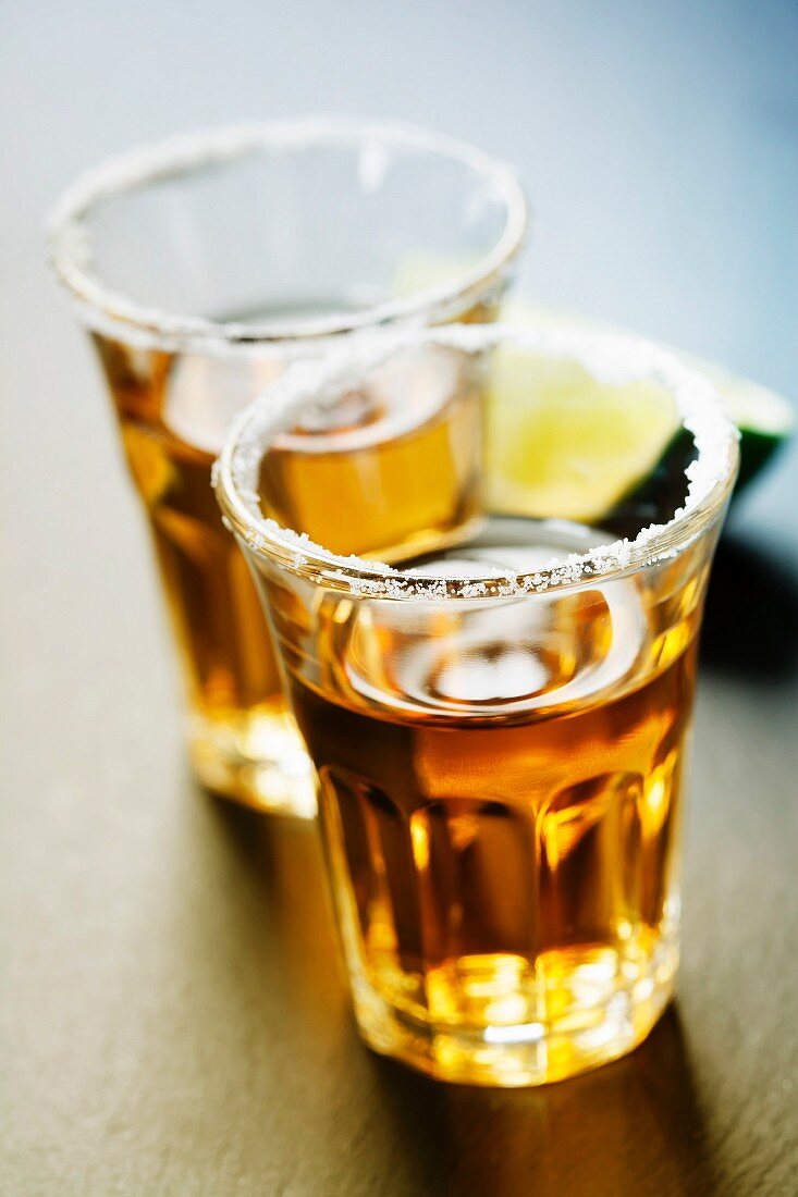 Tequila shots with lime and salt on rustic background